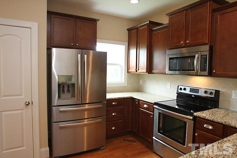 7332 Denlee Road Raleigh, NC 27603 - Photo 10 of 24 a kitchen with granite countertop stainless steel appliances and wooden cabinets