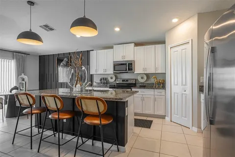 a kitchen with stainless steel appliances granite countertop a refrigerator a stove a sink and a microwave