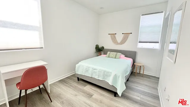 a bedroom with a bed a chair and dresser next to a window