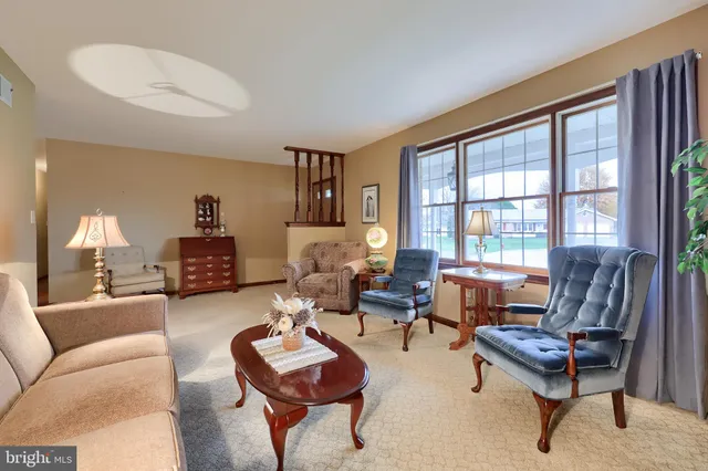 a living room with furniture a lamp paintings and a window