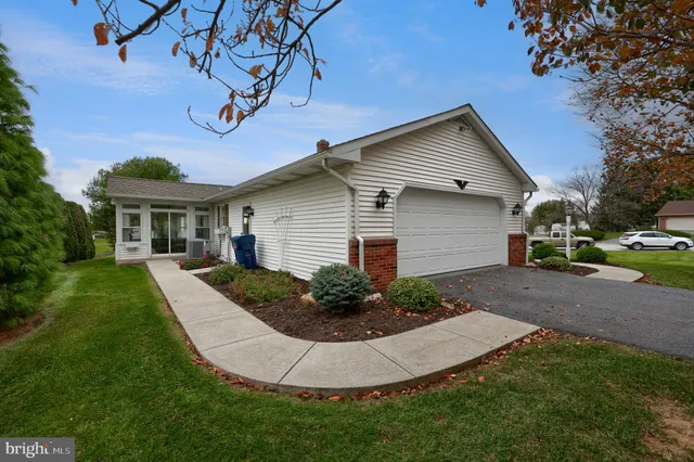 a view of a white house next to a yard and a large tree