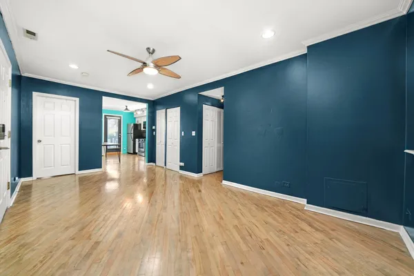 a view of empty room with wooden floor and fan