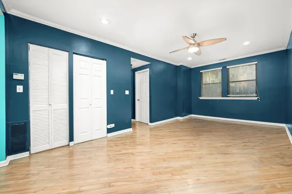 a view of empty room with wooden floor and fan