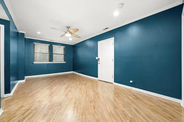 a view of empty room with wooden floor and fan