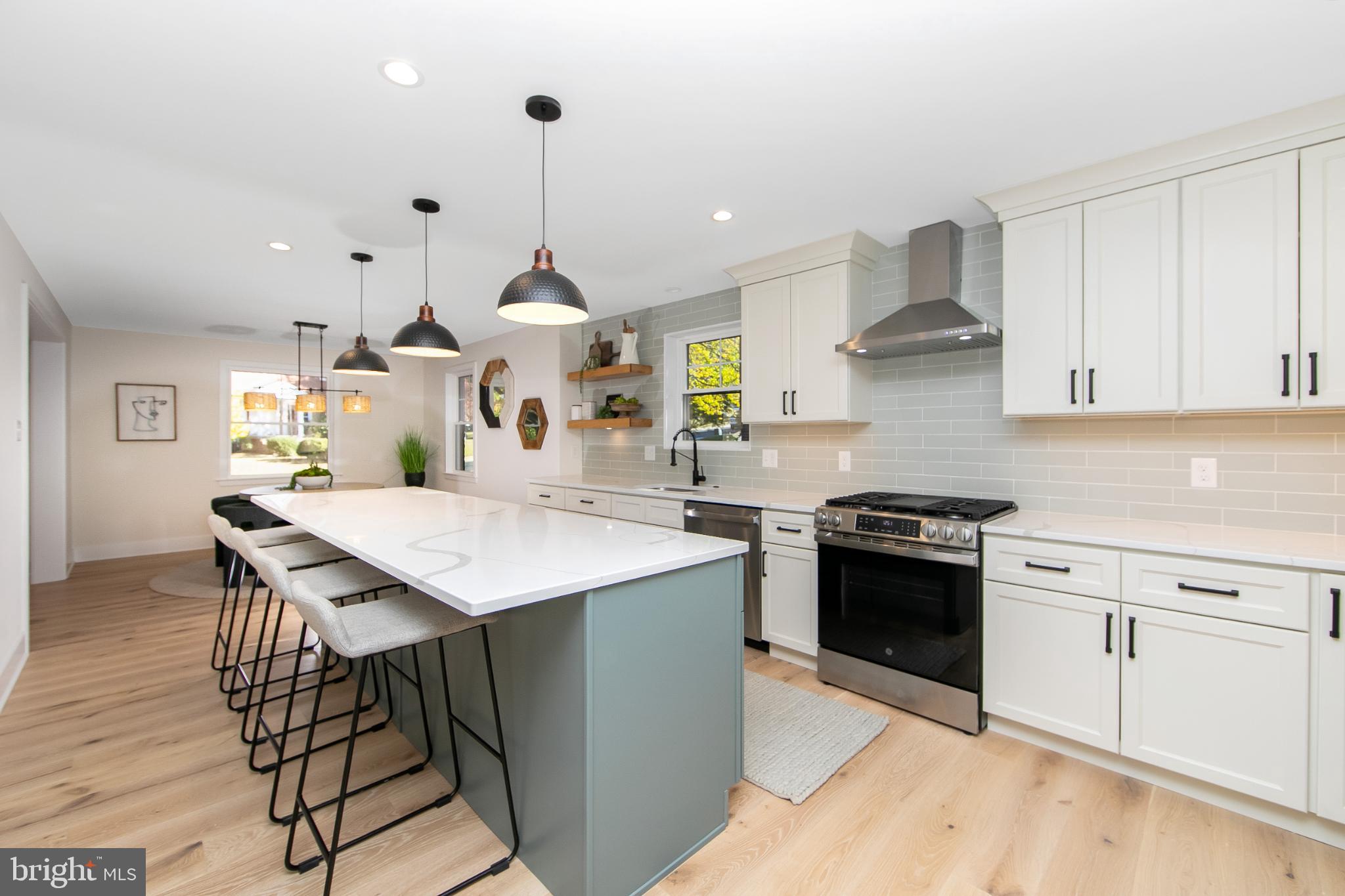 22 Scenic Road Springfield, PA 19064 - Photo 13 of 56 a kitchen with stainless steel appliances kitchen island a table chairs in it and white cabinets