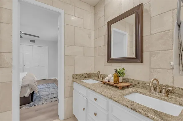 a bathroom with a granite countertop sink a mirror and shower