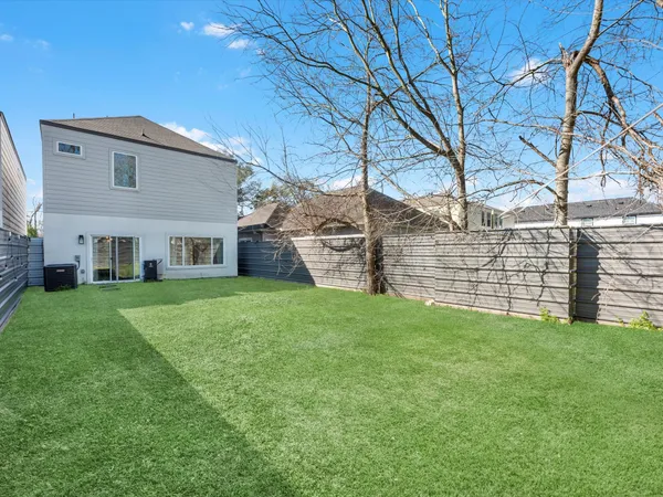 a view of a yard in front of a house with plants and large tree
