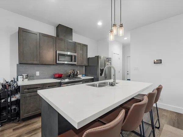 a kitchen that has a table chairs stainless steel appliances and cabinets