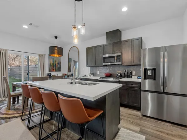 a kitchen with stainless steel appliances granite countertop a dining table chairs refrigerator and cabinets
