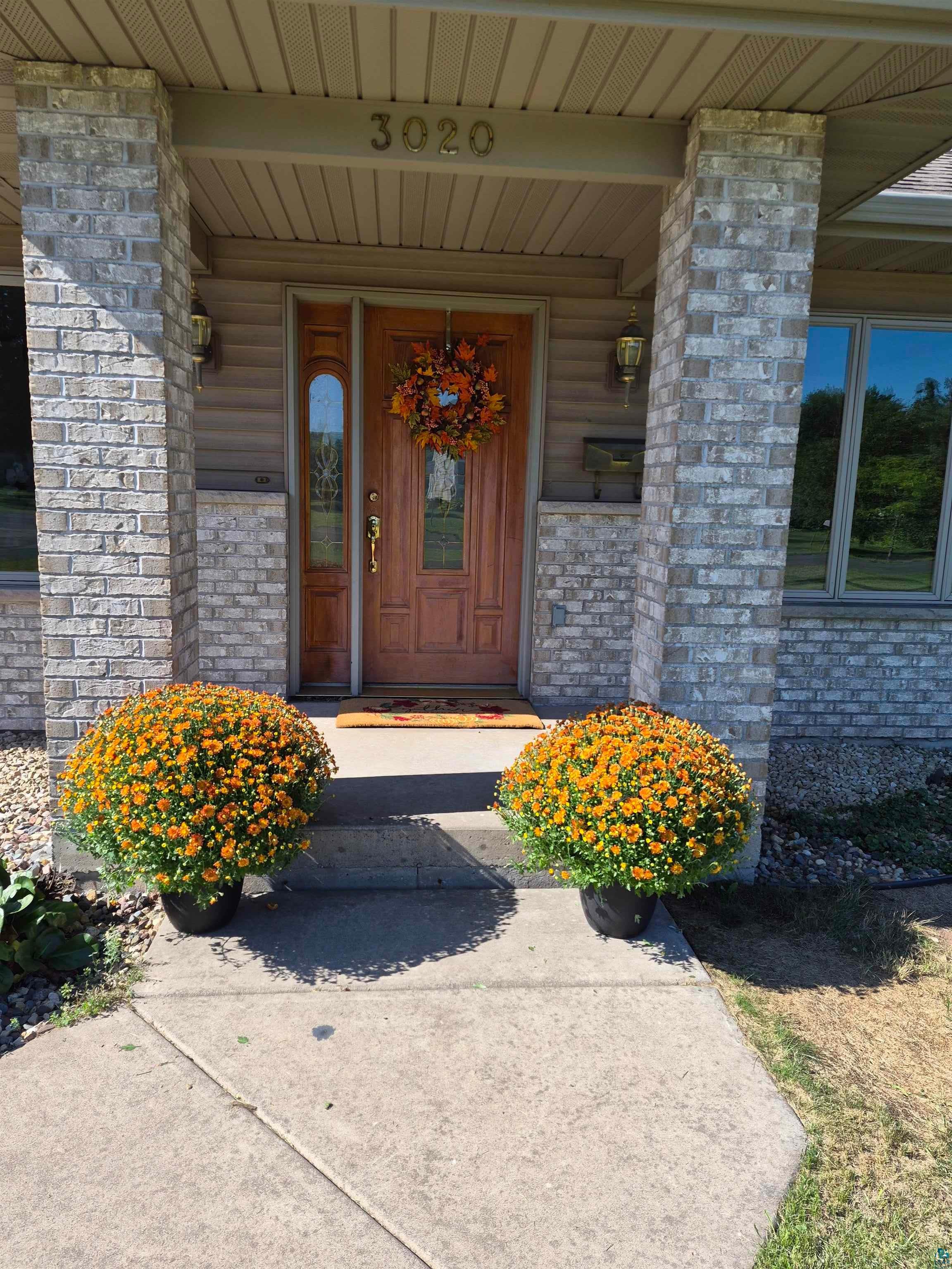 3020 East 8th Street Superior, WI 54880 - Photo 1 of 37 Entryway featuring a wood-panel door with sidelight, brick columns, and concrete walkway