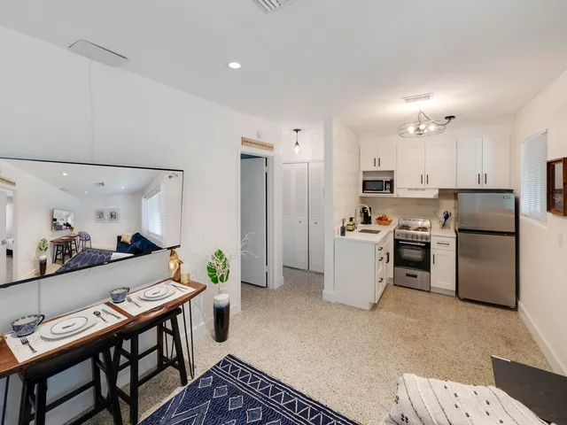 a kitchen with a refrigerator a stove top oven a sink dishwasher and dining table with wooden floor