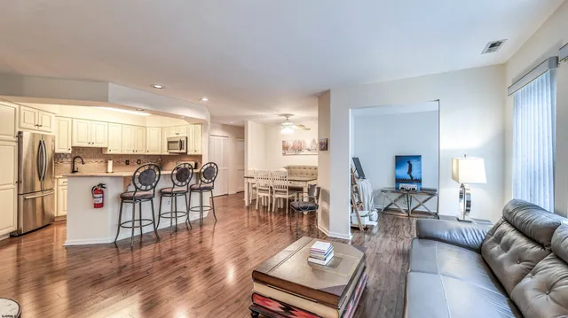 a living room with furniture kitchen view and a wooden floor