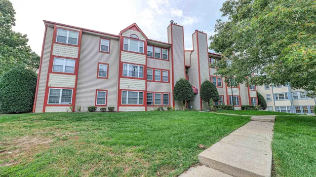 a view of a building next to a big yard and large trees