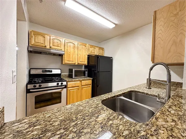 a kitchen with stainless steel appliances granite countertop a sink stove and refrigerator