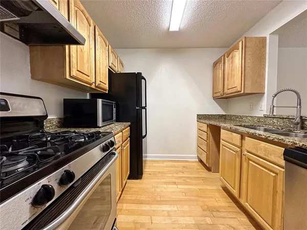 a kitchen with stainless steel appliances granite countertop a stove a sink dishwasher and a refrigerator