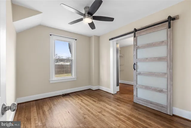 a view of empty room with wooden floor and fan