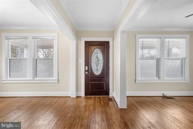 an empty room with wooden floor closet and windows