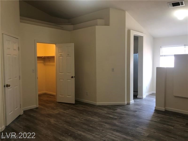 838 Rusty Anchor Way Henderson, NV 89002 - Photo 12 of 18 Unfurnished bedroom featuring vaulted ceiling, dark wood-style floors, and a walk in closet