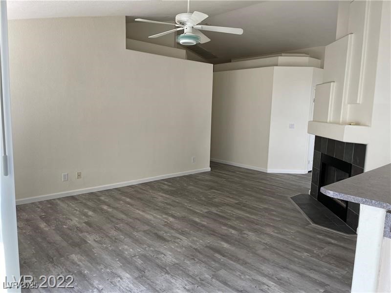 838 Rusty Anchor Way Henderson, NV 89002 - Photo 7 of 18 Unfurnished living room with dark wood-style flooring, a tile fireplace, and ceiling fan