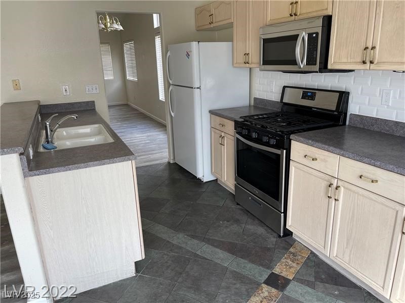 838 Rusty Anchor Way Henderson, NV 89002 - Photo 8 of 18 Kitchen featuring dark countertops, stainless steel appliances, tasteful backsplash, and a chandelier