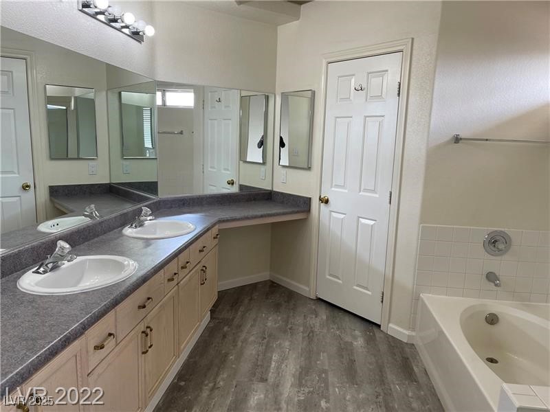 838 Rusty Anchor Way Henderson, NV 89002 - Photo 9 of 18 Bathroom with double vanity, a garden tub, and dark wood-style floors
