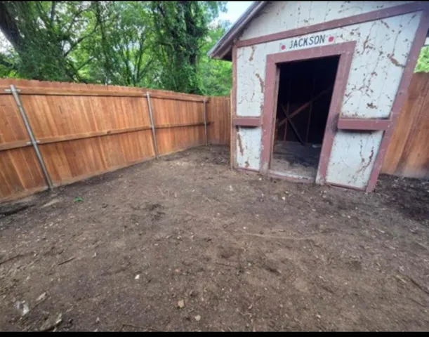 a view of backyard with small cabin and wooden fencing