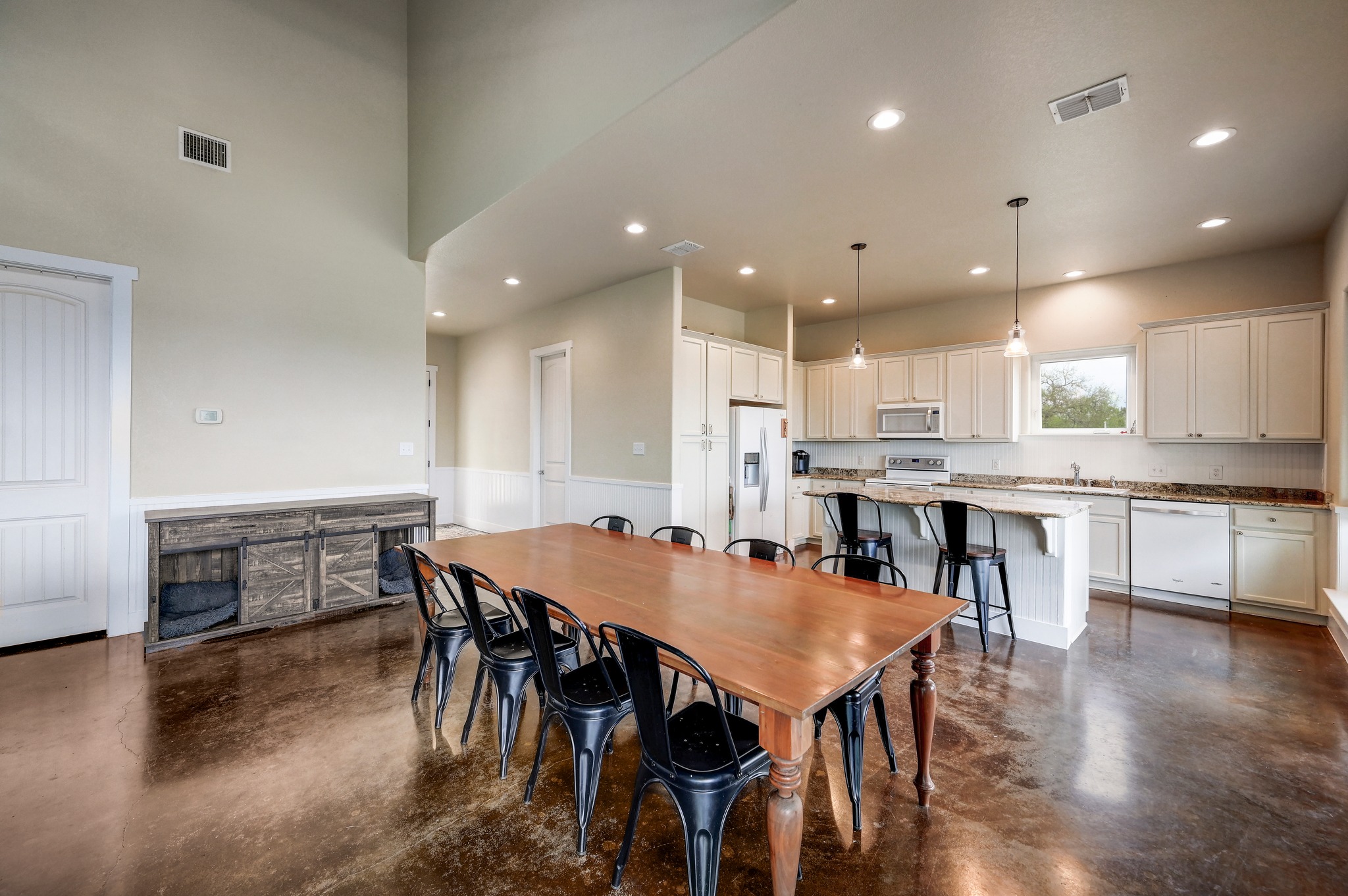 6350 Mt Sharp Road, Unit B Wimberley, TX 78676 - Photo 6 of 34 an open kitchen with kitchen island a dining table chairs and white cabinets