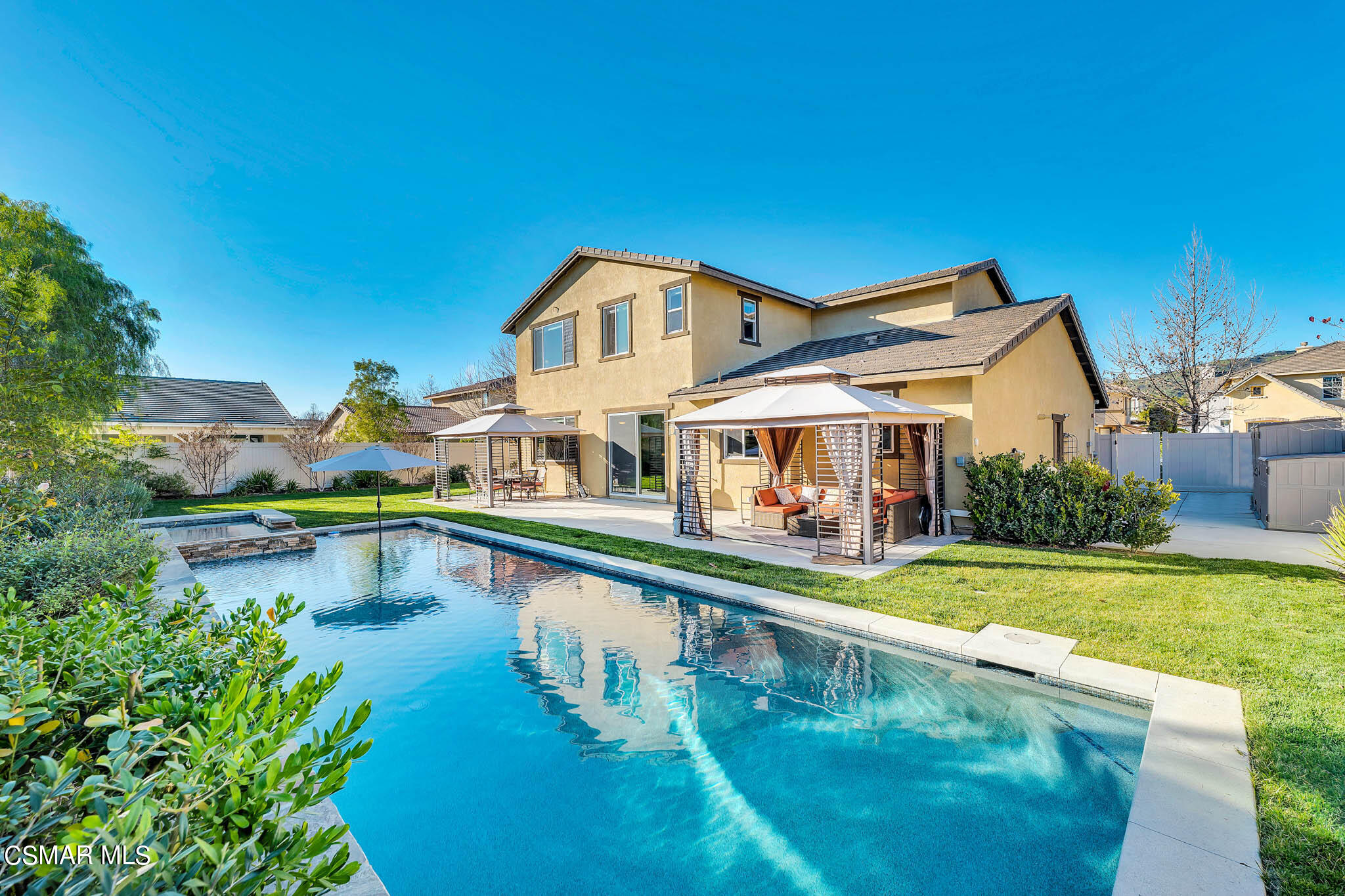 a view of a swimming pool with lawn chairs and plants