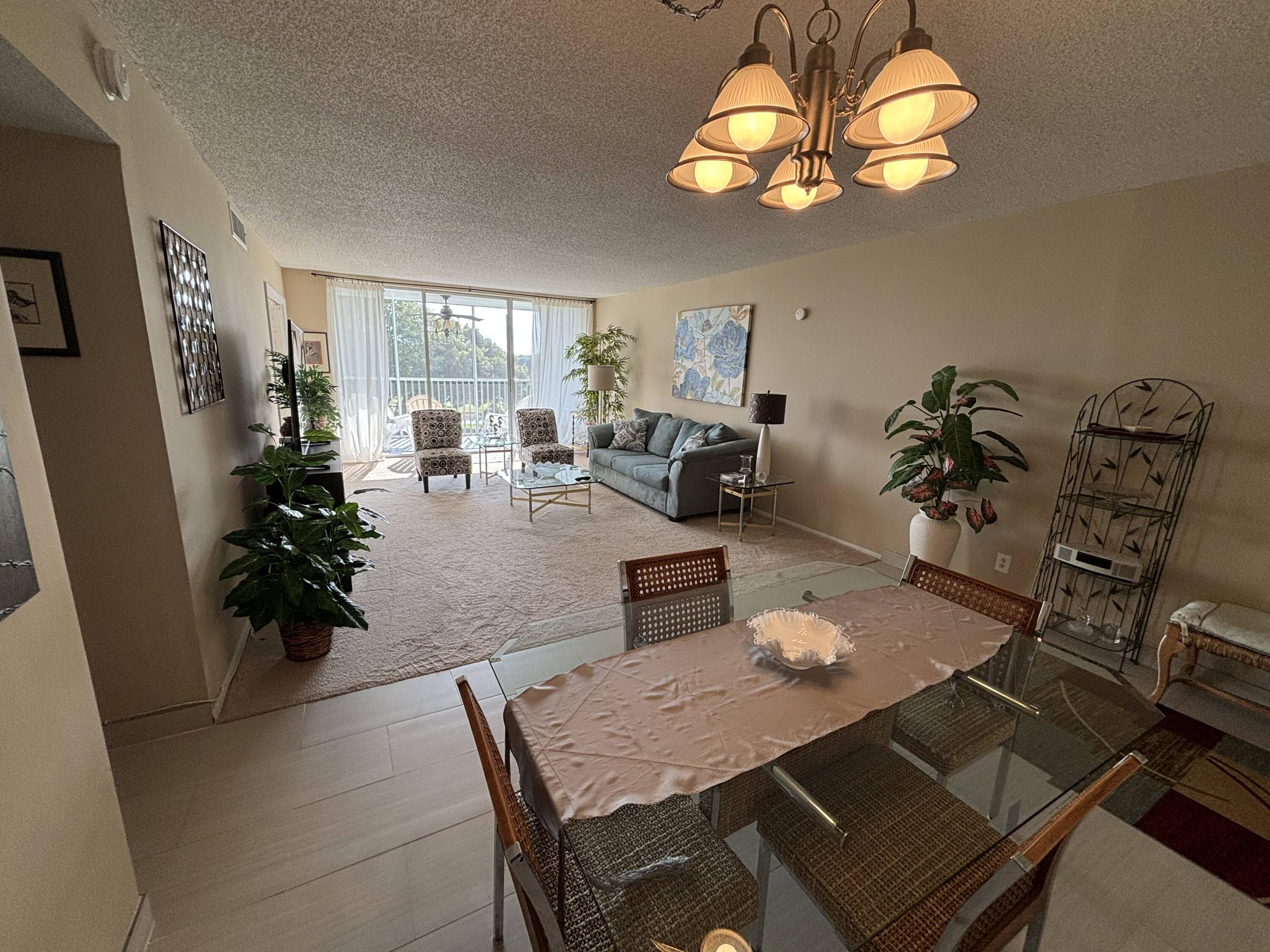 2691 South Course Drive, Unit 408 Pompano Beach, FL 33069 - Photo 22 of 24 a view of a dining room with furniture a chandelier windows and wooden floor