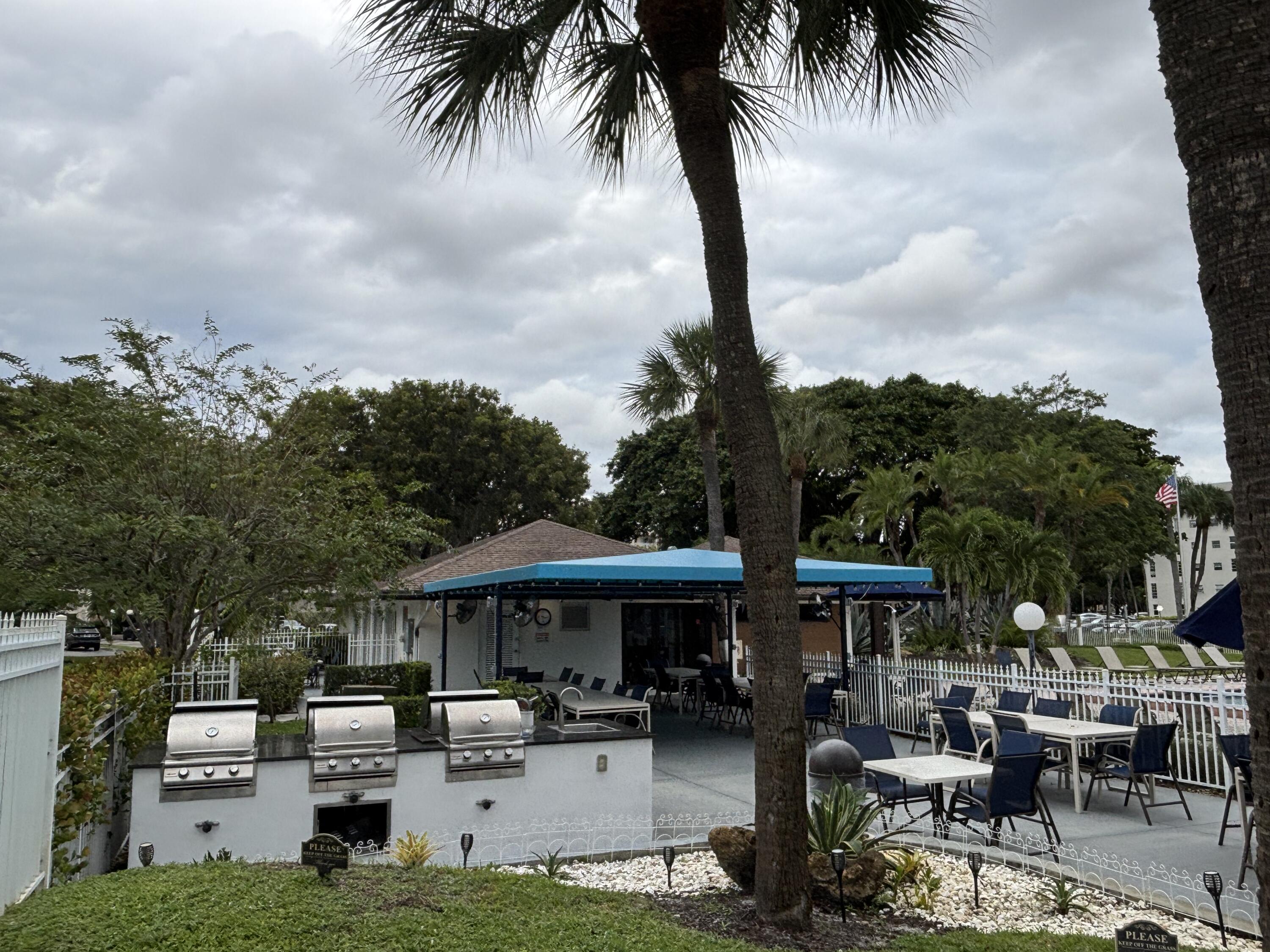 2691 South Course Drive, Unit 408 Pompano Beach, FL 33069 - Photo 3 of 24 a patio with tables and chairs pool and a fire pit