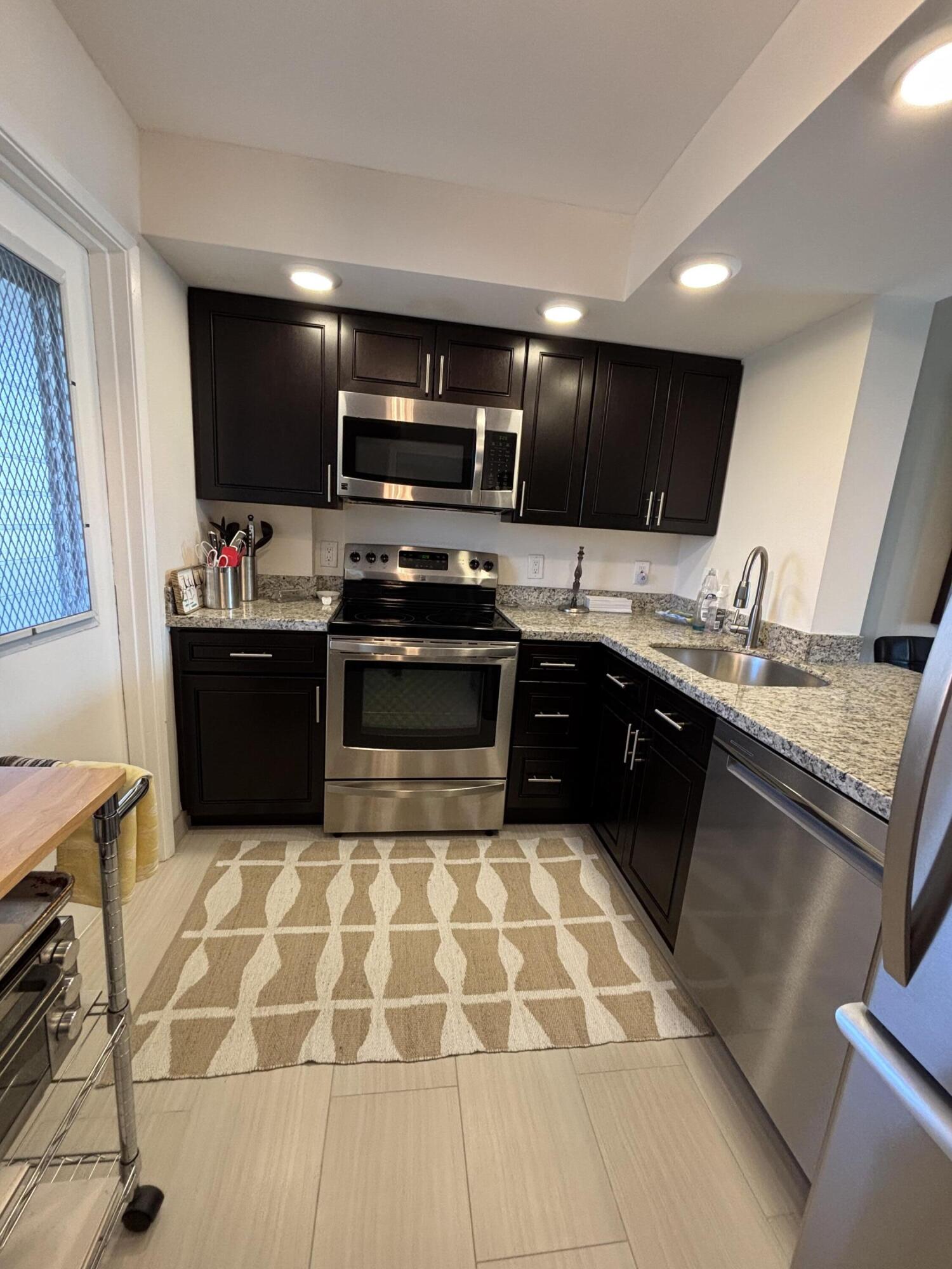 2691 South Course Drive, Unit 408 Pompano Beach, FL 33069 - Photo 7 of 24 a kitchen with stainless steel appliances kitchen island granite countertop a sink dishwasher stove top oven and cabinets