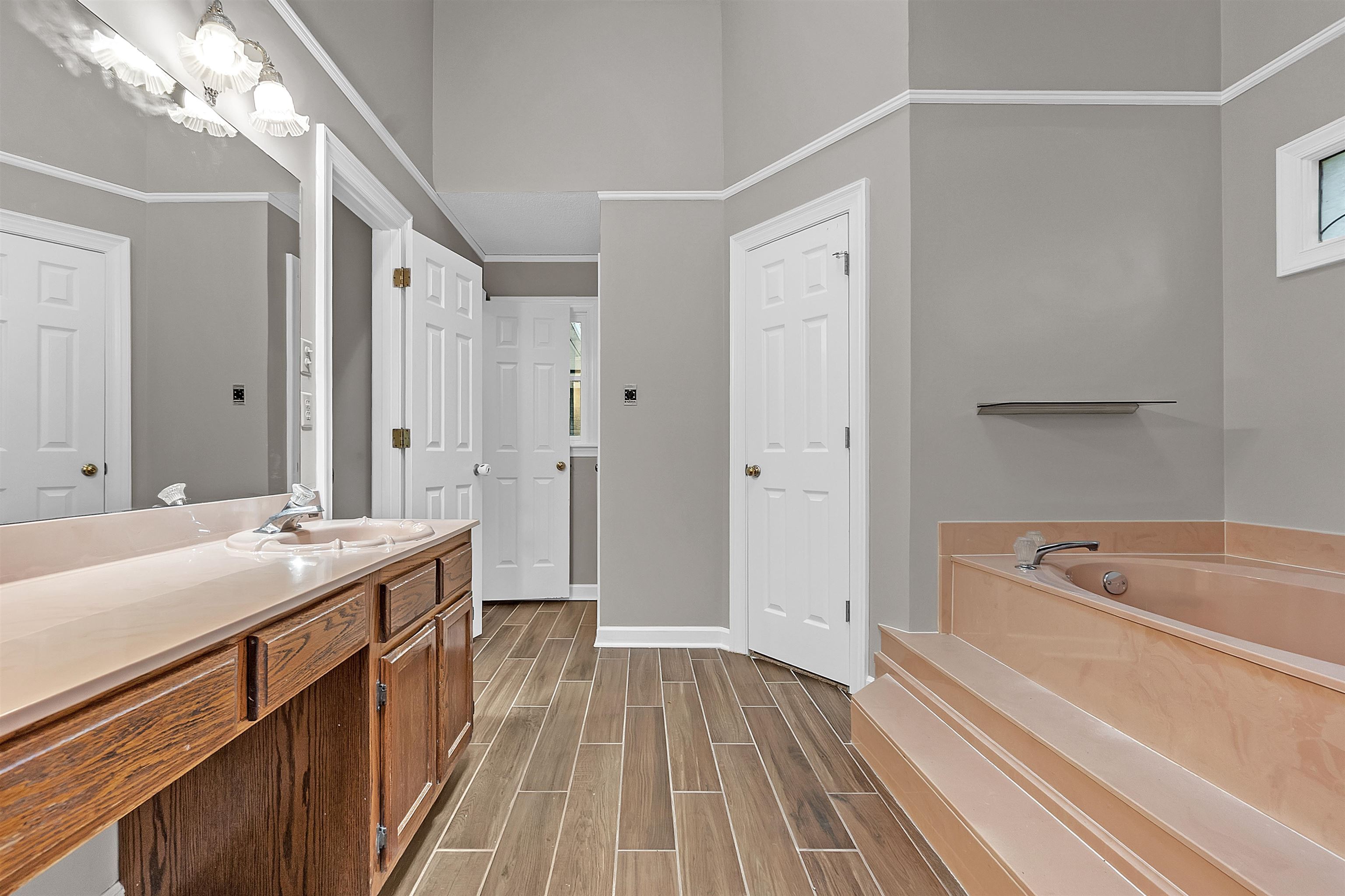 400 Reksten Cove Memphis, TN 38018 - Photo 19 of 26 Bathroom vanity featuring an integrated sink, wood-finish cabinetry, and a large mirror with overhead lighting