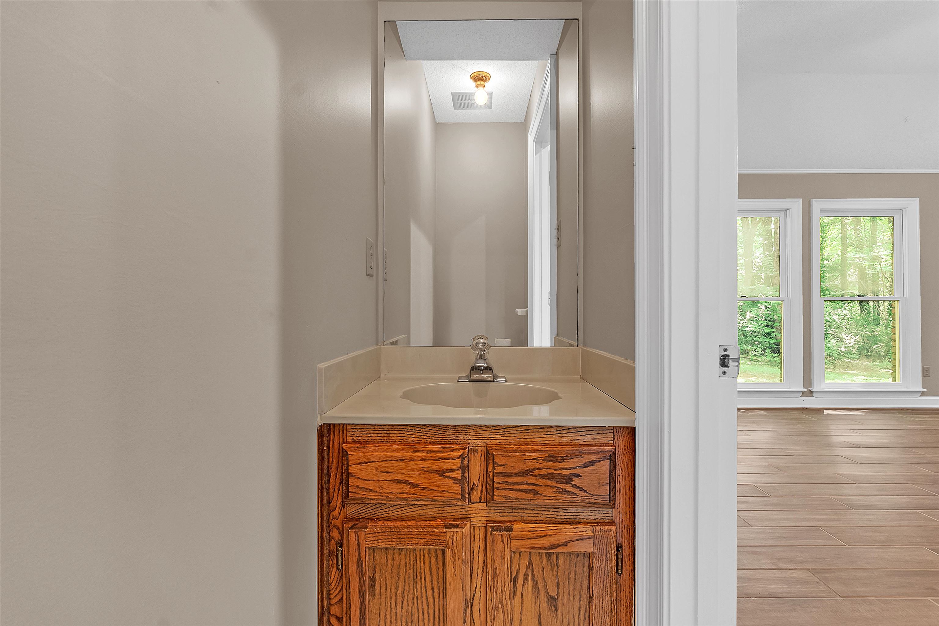 400 Reksten Cove Memphis, TN 38018 - Photo 23 of 26 Powder room featuring a wood-finish vanity with a built-in sink and a framed mirror