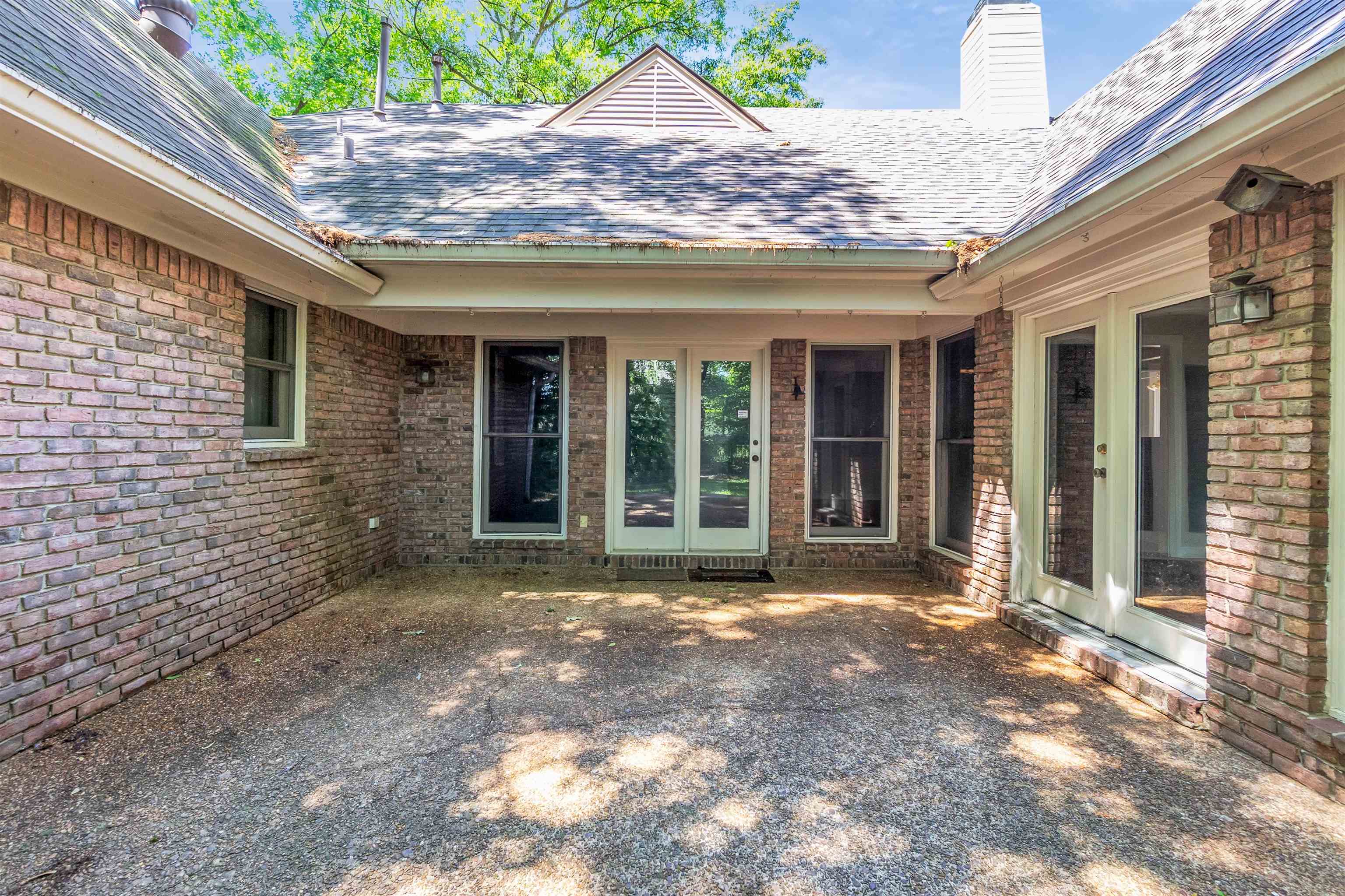 400 Reksten Cove Memphis, TN 38018 - Photo 25 of 26 Expansive brick exterior patio featuring a concrete surface, multiple glass panel doors, a gable roofline, and an exterior wall lantern