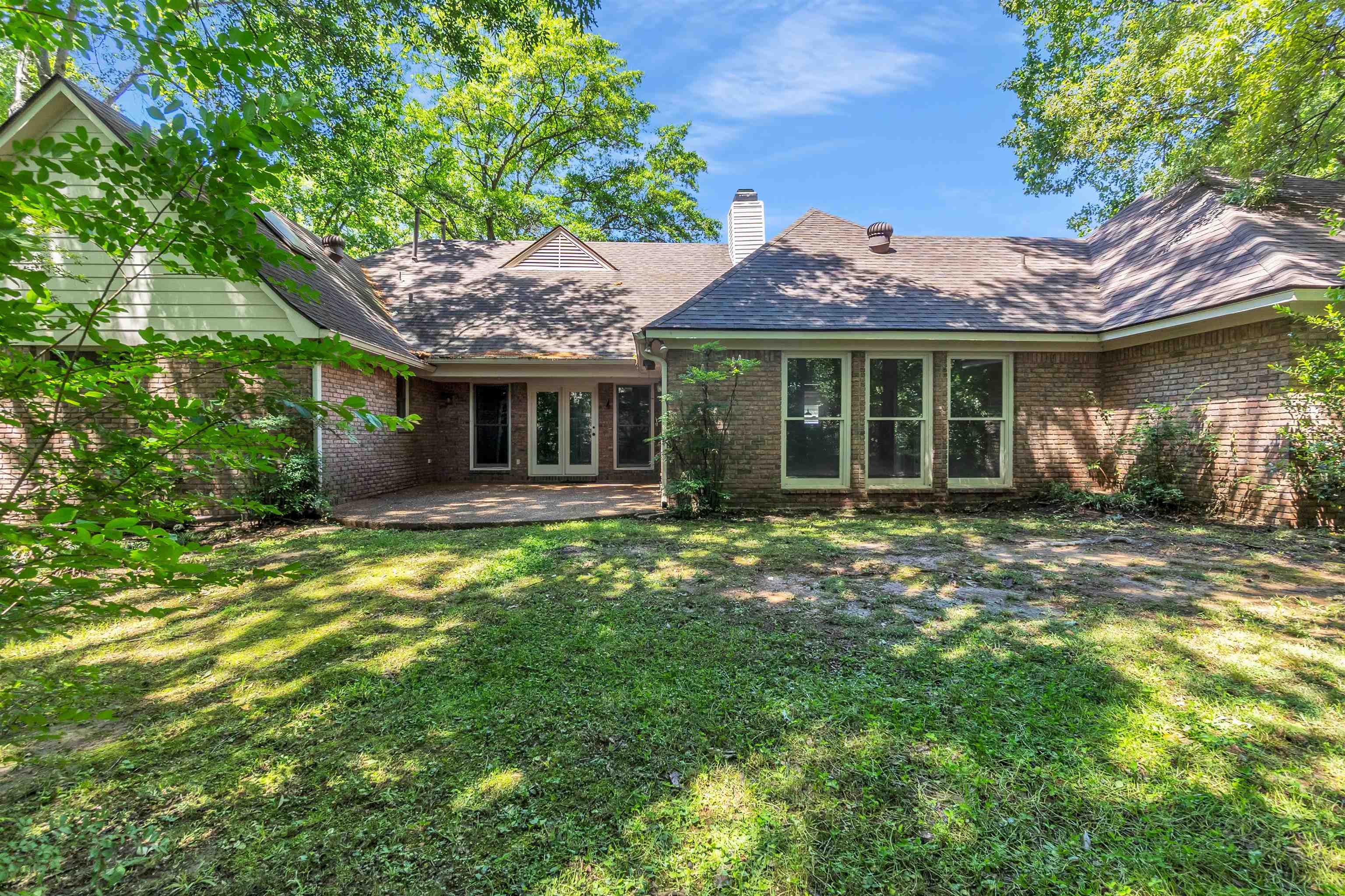 400 Reksten Cove Memphis, TN 38018 - Photo 26 of 26 Expansive backyard featuring a brick exterior, multiple windows, and a patio area