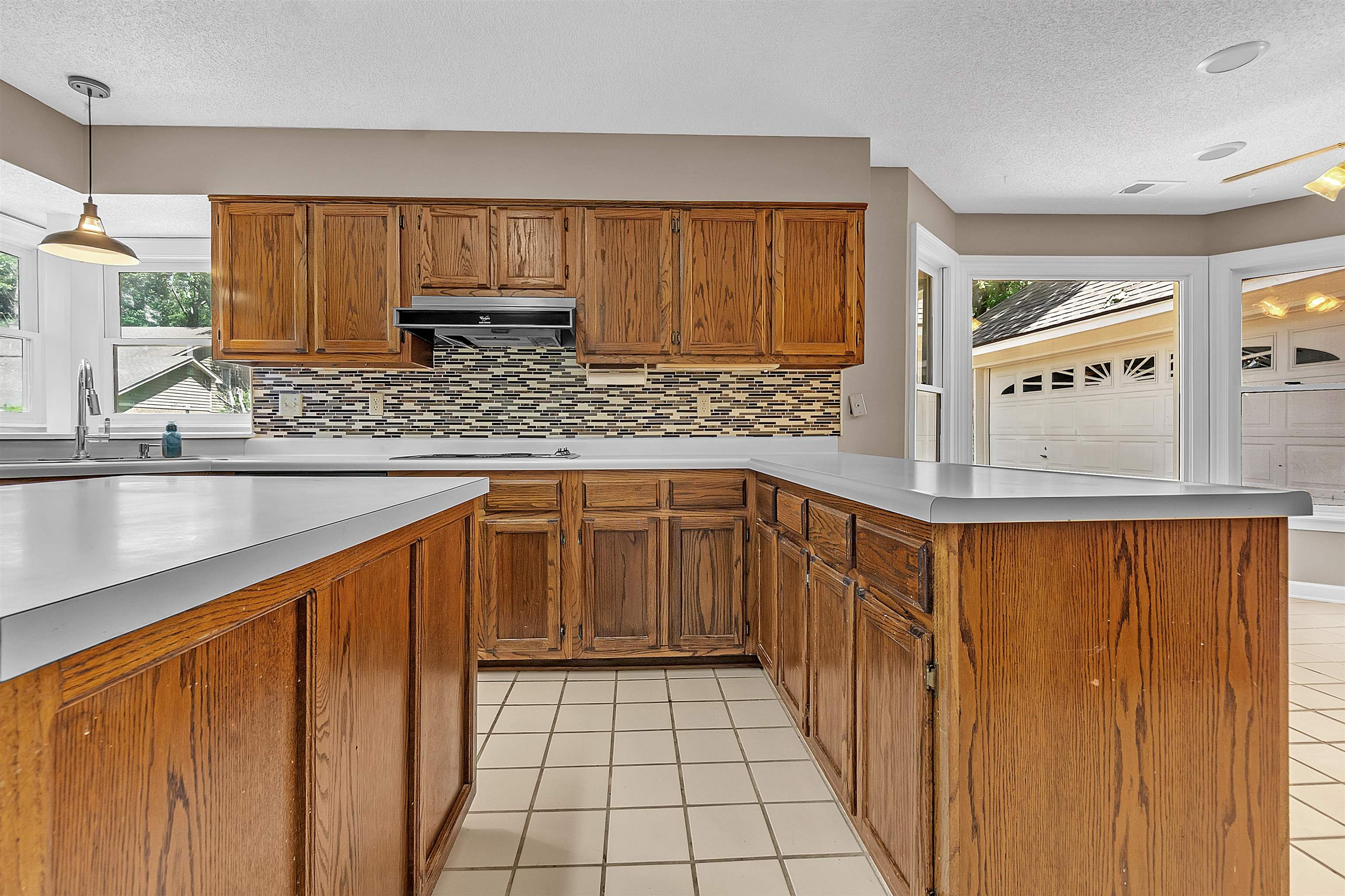 400 Reksten Cove Memphis, TN 38018 - Photo 10 of 26 Kitchen featuring wood cabinetry, white countertops, a mosaic tile backsplash, and ceramic tile flooring