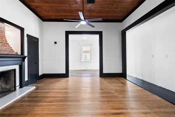 a view of an empty room with wooden floor fireplace and a window