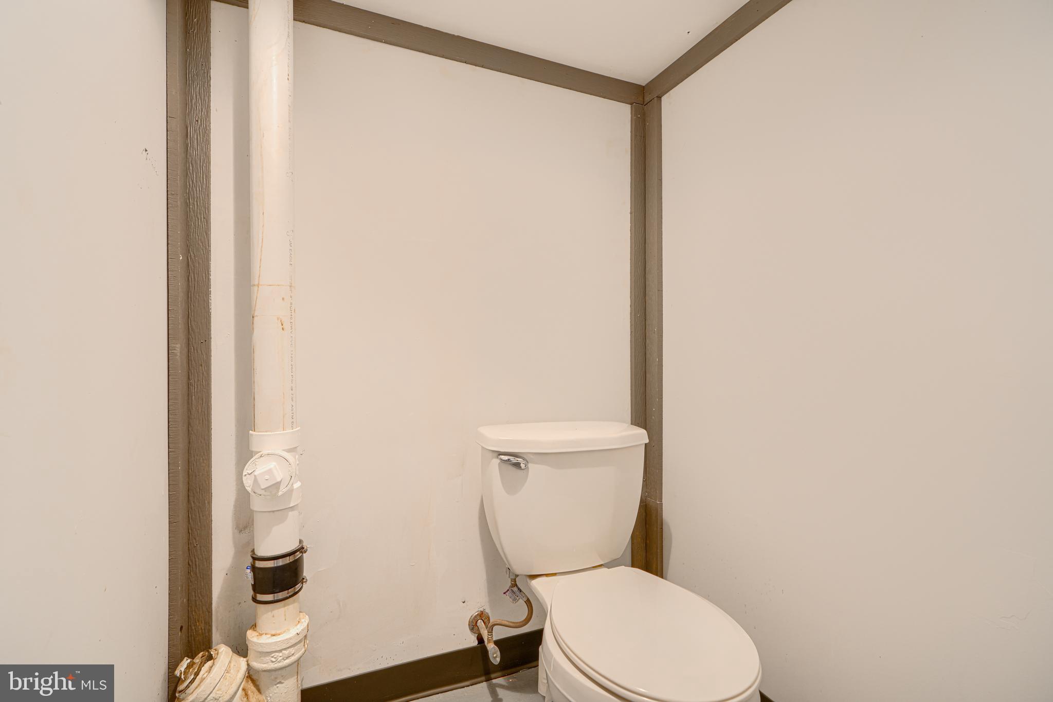6905 Bank Street Baltimore, MD 21224 - Photo 15 of 17 a white toilet sitting next to a shower curtain
