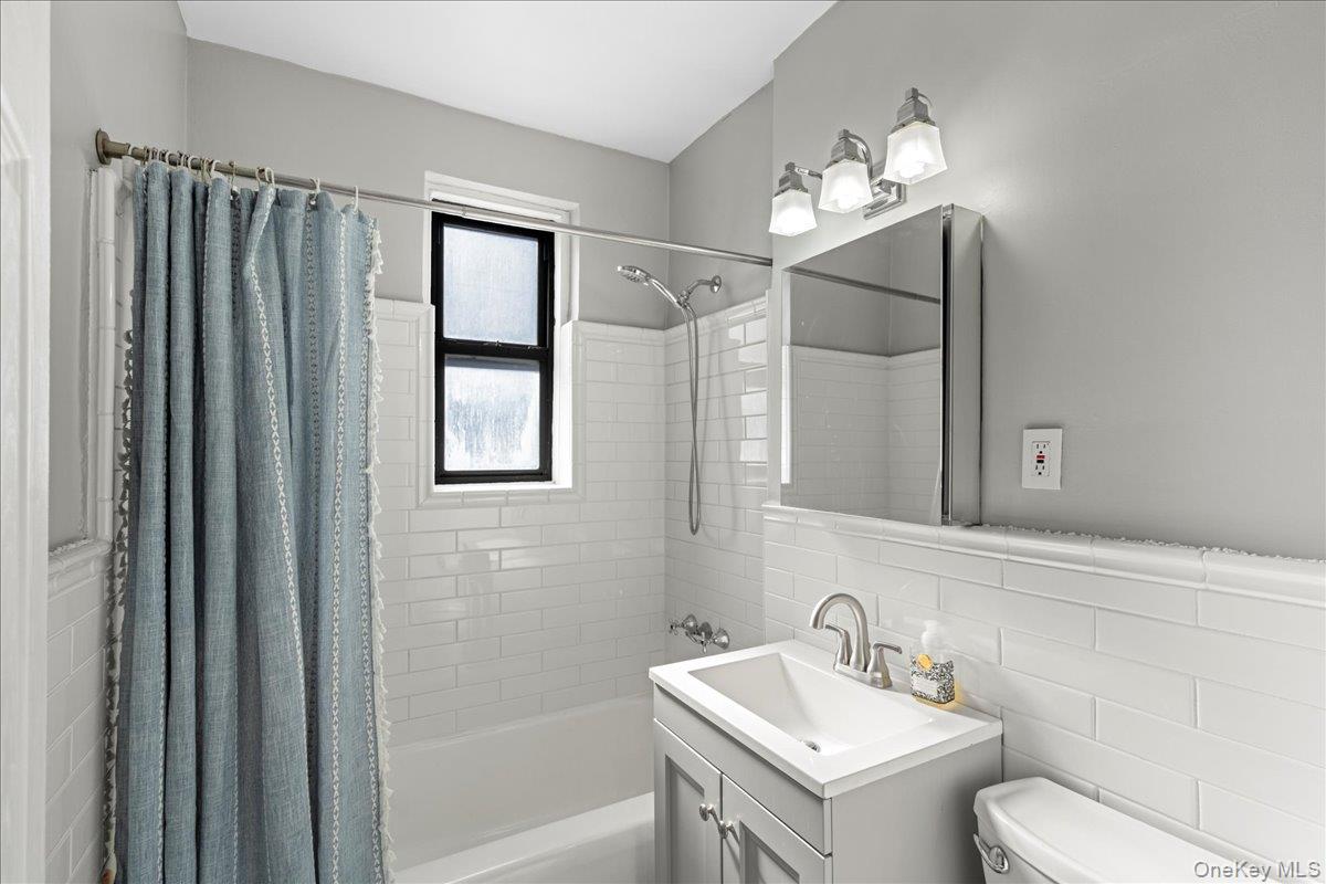 110-45 71st Road, Unit 6D Queens, NY 11375 - Photo 12 of 20 Bathroom featuring tile walls, vanity, and shower / bath combo with shower curtain