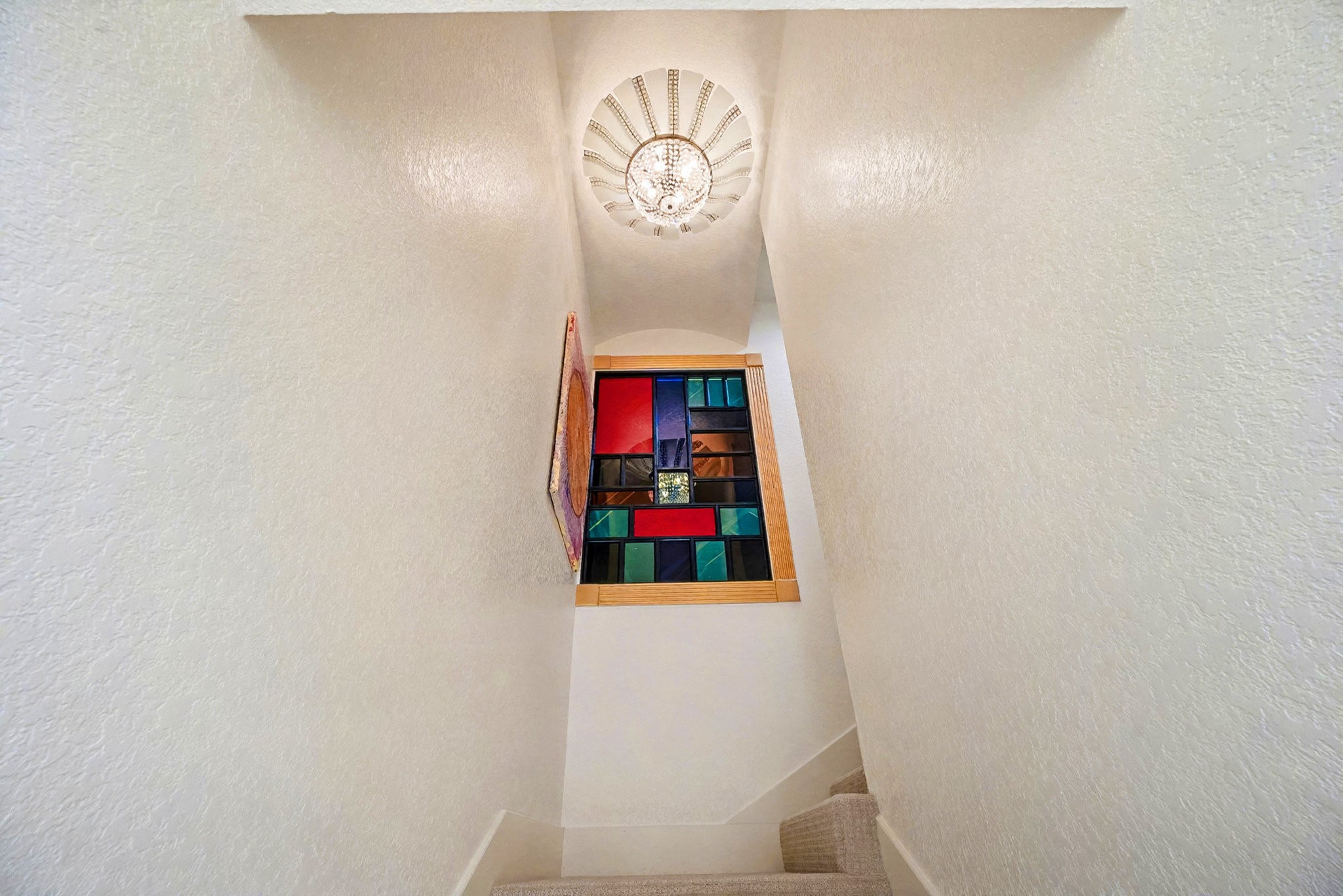 1200 Davenport Parkway Rosharon, TX 77583 - Photo 21 of 49 Stairway to second floor from kitchen area with custom stained-glass window and elegant Burbank carpet runner,
illuminated by a crystal chandelier.