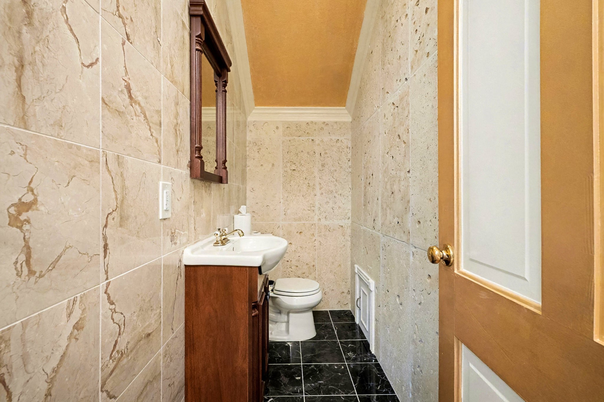 1200 Davenport Parkway Rosharon, TX 77583 - Photo 26 of 49 Half bath (1) with marble wall tile and limestone fossil shell finish, featuring a classic
wood vanity, gold fixtures, and black marble flooring.