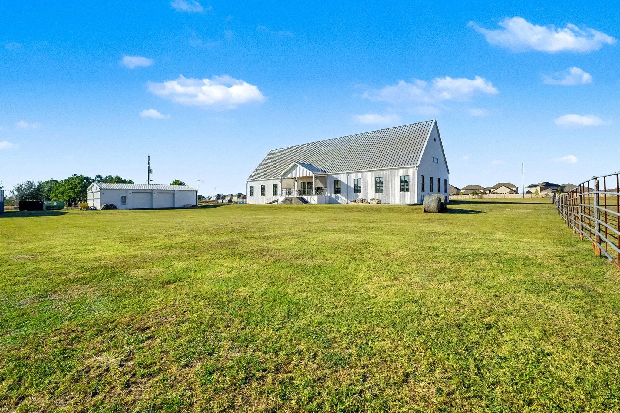 1200 Davenport Parkway Rosharon, TX 77583 - Photo 42 of 49 Expansive back view of the home nestled on 3.5 acres, displaying its impressive architectural metal
roof and wide-open lawn. The second angle highlights the detached garage,
perfectly complementing the property’s spacious, functional layout.