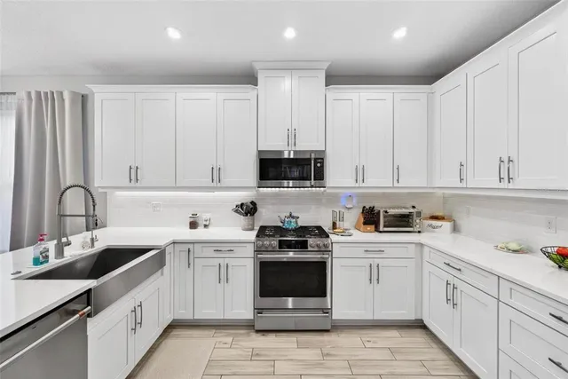 a kitchen with white cabinets and stainless steel appliances