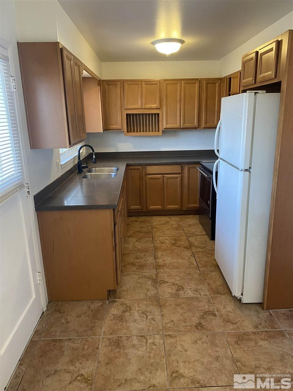 1165 Manhattan Street Reno, NV 89512 - Photo 5 of 14 a kitchen with granite countertop a refrigerator and a sink