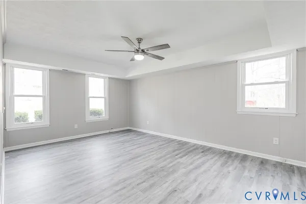 a view of empty room with wooden floor and fan