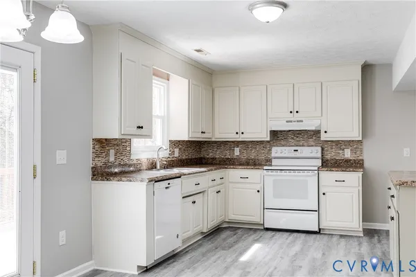 a kitchen with granite countertop white cabinets sink and stainless steel appliances