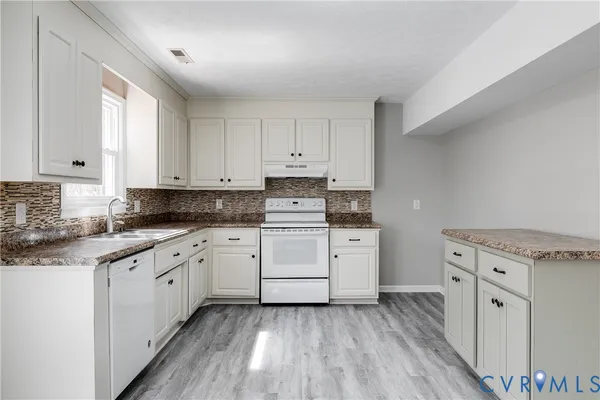 a kitchen with granite countertop white cabinets and white appliances