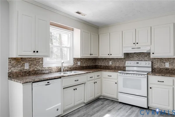 a kitchen with granite countertop white cabinets white appliances and a sink