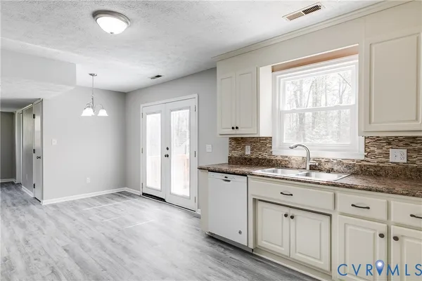 a kitchen with granite countertop a sink cabinets wooden floor and a window