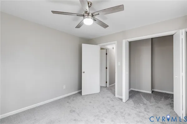 an empty room with closet and a ceiling fan
